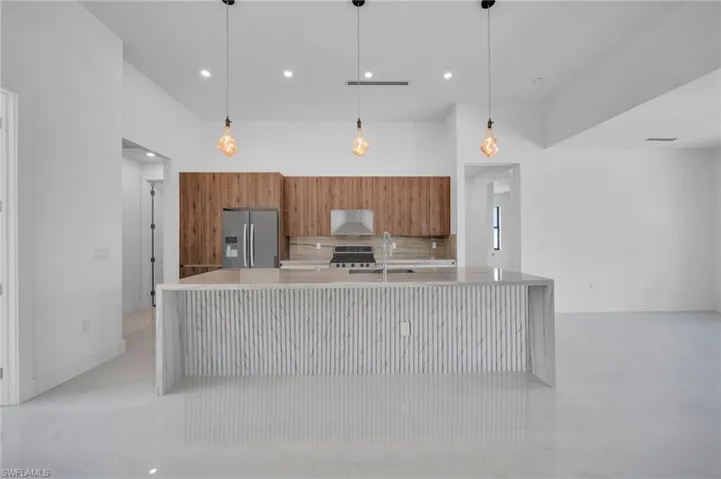 Kitchen featuring stainless steel fridge, brown cabinets, modern cabinets, light countertops, and stove
