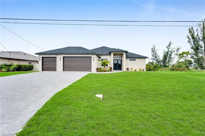 Prairie-style home featuring a front lawn, decorative driveway, a garage, stucco siding, and a shingled roof