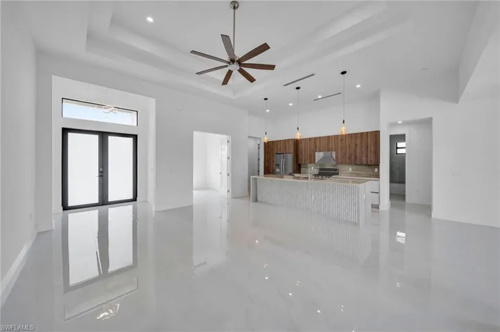Kitchen with stainless steel fridge, modern cabinets, a raised ceiling, a towering ceiling, and tasteful backsplash