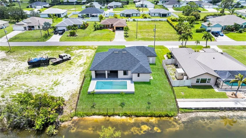 Aerial view of residential area featuring a large body of water and a pool