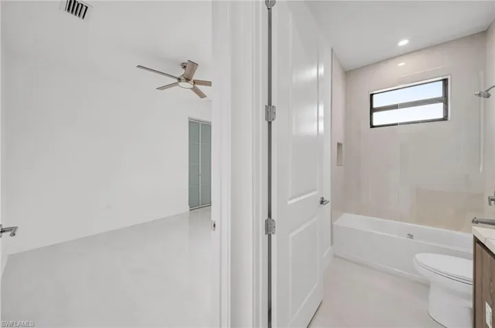 Full bathroom featuring vanity, ceiling fan, and shower / washtub combination