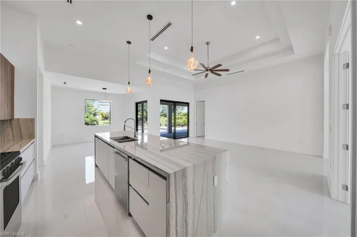Kitchen featuring modern cabinets, appliances with stainless steel finishes, a spacious island, a tray ceiling, and recessed lighting