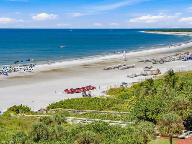 Oceanfront property featuring direct beach access via a private wooden boardwalk, surrounded by coastal vegetation and palm trees