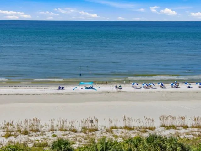 Direct beachfront access featuring white sand, coastal dune vegetation, and expansive ocean scenery