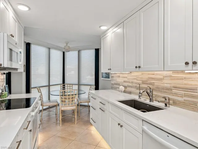 Kitchen featuring white shaker-style cabinetry, quartz countertops, horizontal-tiled backsplash, stainless steel under-mount sink, and recessed lighting