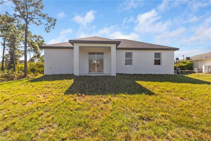 Rear view of property with a yard and stucco siding