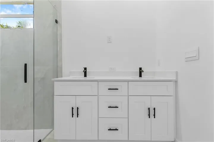Bathroom with double vanity and a marble finish shower