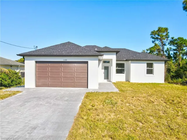 Prairie-style home featuring stucco siding, decorative driveway, a garage, and a front yard