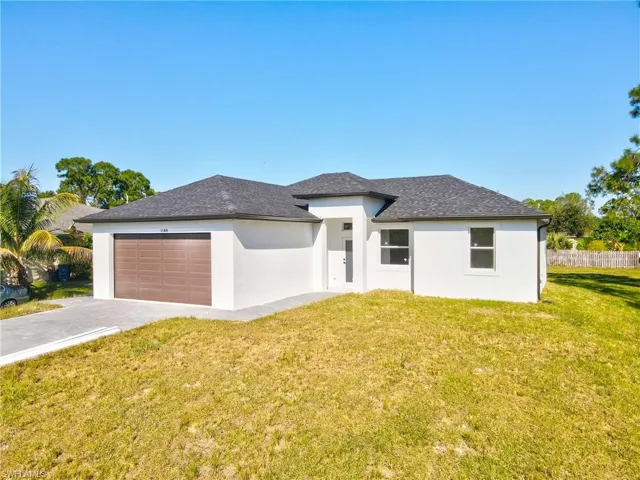 Prairie-style home featuring a front yard, an attached garage, stucco siding, and concrete driveway