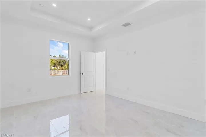 Unfurnished room with a raised ceiling and recessed lighting