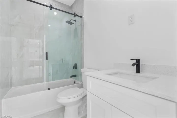 Full bathroom featuring vanity and bath / shower combo with glass door
