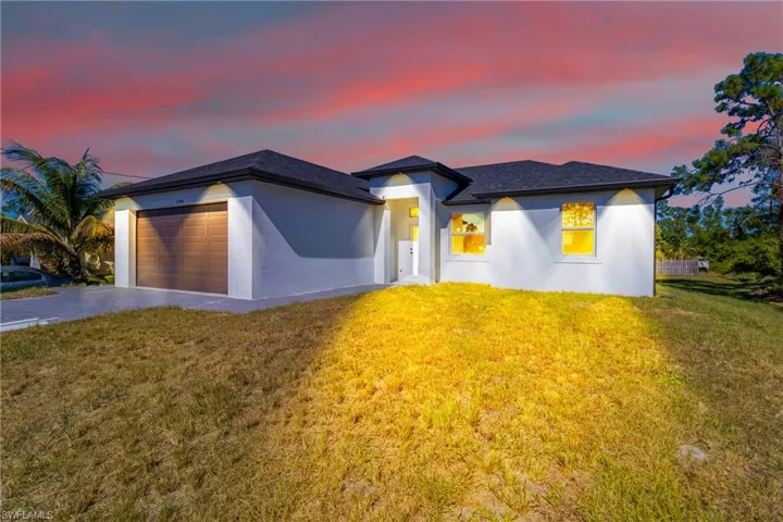 View of front of home with a lawn, stucco siding, an attached garage, and concrete driveway