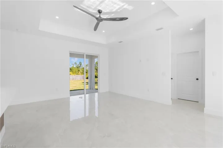Empty room featuring a ceiling fan, a raised ceiling, and recessed lighting