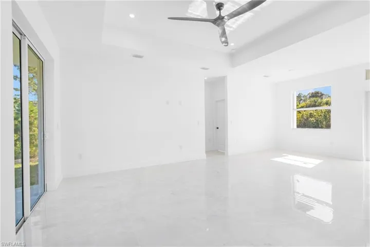 Empty room with ceiling fan, a tray ceiling, and recessed lighting