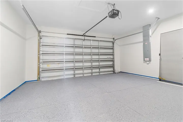 Garage featuring a garage door opener and electric panel