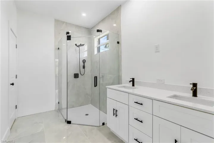 Bathroom with double vanity, a marble finish shower, and recessed lighting