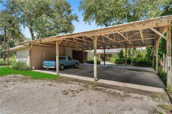Pole barn covered parking with enclosed work area and stable in background