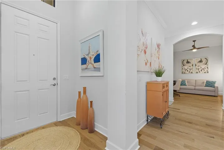 Hall with light wood finished floors and crown molding