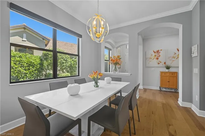 Dining space with wood finished floors, ornamental molding, and a chandelier