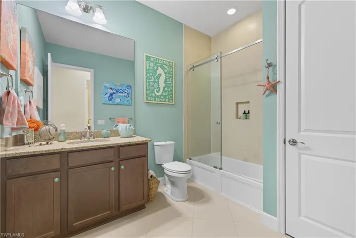 Bathroom with vanity, shower / bath combination with glass door, light tile patterned flooring, and recessed lighting