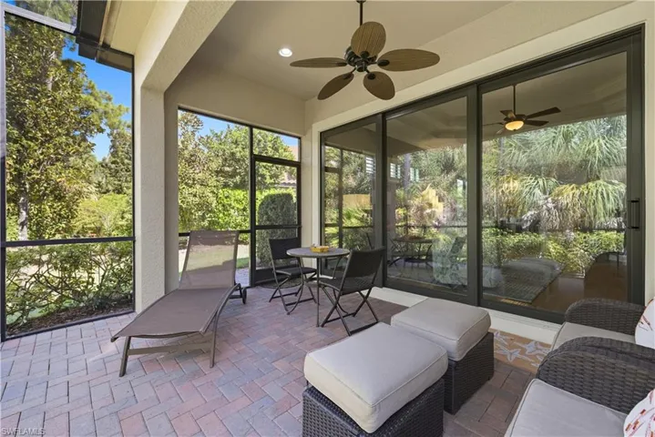 Sunroom with a ceiling fan, plenty of natural light, and view of scattered trees