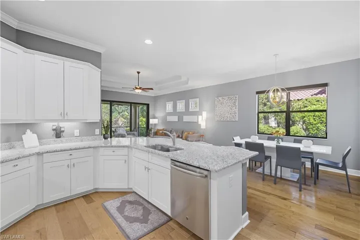 Kitchen featuring stainless steel dishwasher, ornamental molding, white cabinets, light wood-style floors, and a ceiling fan