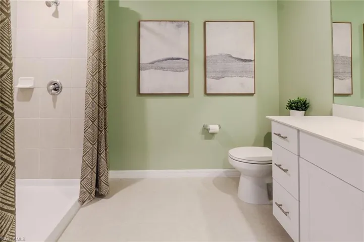 Full bathroom featuring a white single vanity with a solid surface countertop, an undermount sink, and brushed nickel hardware