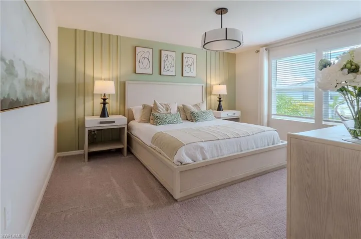Carpeted bedroom featuring a decorative accent wall, a drum pendant light fixture, and large windows with blinds