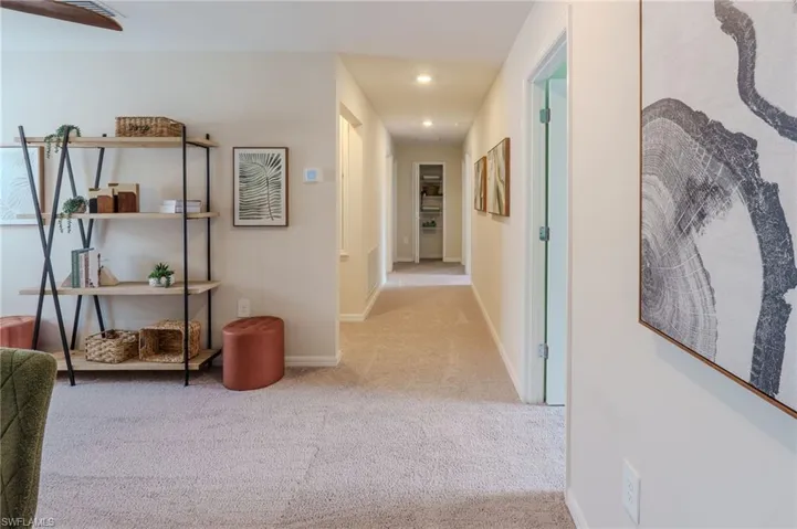 Carpeted hallway with recessed lighting and neutral wall tones