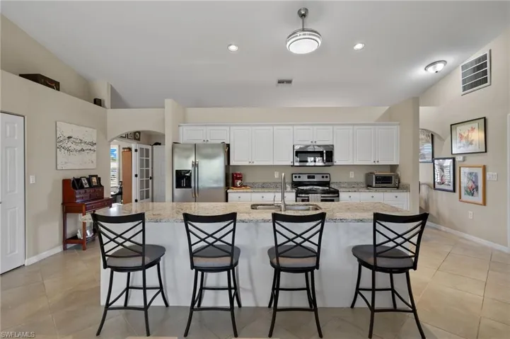 Kitchen with a breakfast bar area, a kitchen island with sink, stainless steel appliances, sink, and white cabinets