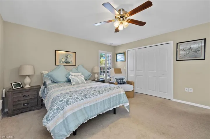 Bedroom featuring light colored carpet, ceiling fan, and a closet
