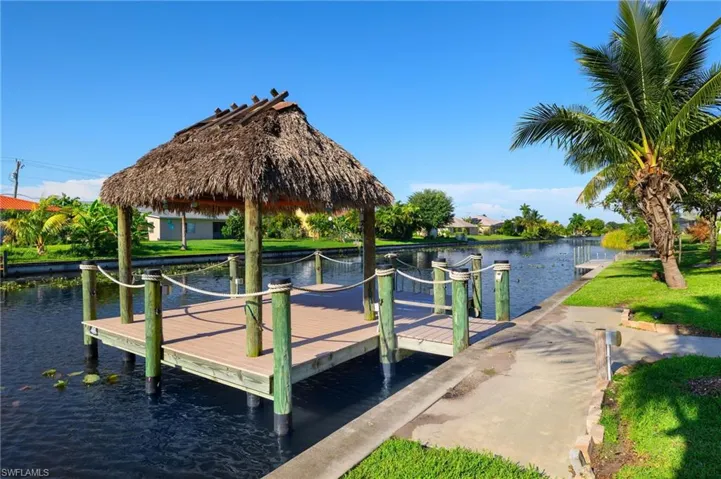 View of dock with a gazebo, a lawn, and a water view