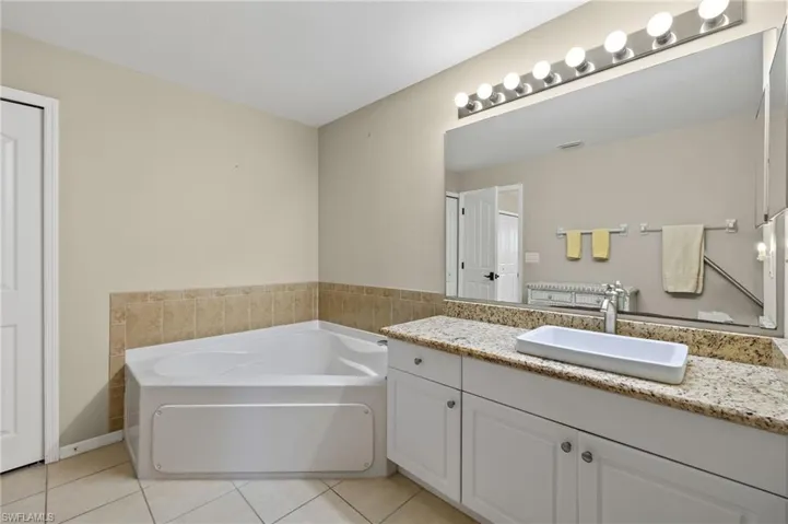 Bathroom with a tub to relax in, vanity, and tile patterned flooring