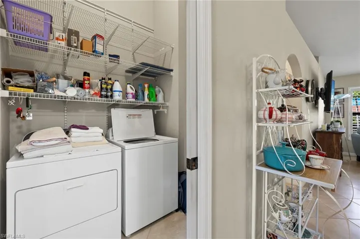 Laundry area with washer and clothes dryer and light tile patterned flooring