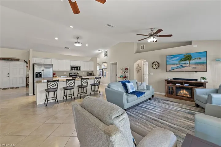Tiled living room with ceiling fan and vaulted ceiling