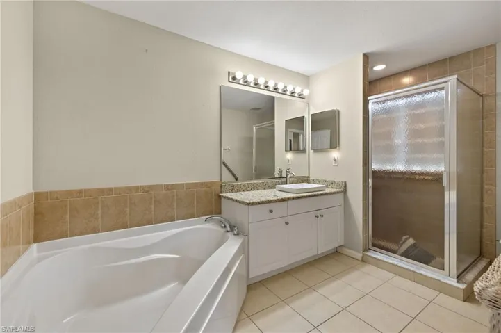 Bathroom featuring vanity, tile patterned floors, and shower with separate bathtub