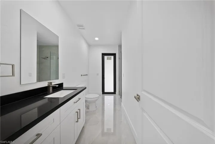 Full bathroom featuring vanity, a shower stall, recessed lighting, and light marble finish flooring