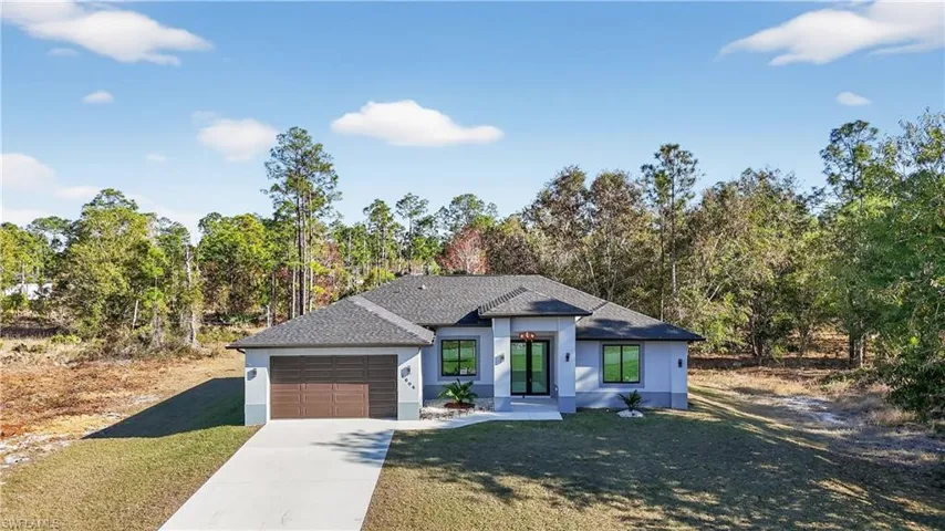 View of front facade with stucco siding, driveway, a front lawn, and an attached garage