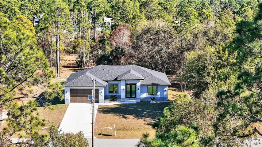 View of front of house with an attached garage, driveway, and roof with shingles