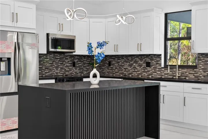 Kitchen featuring stainless steel appliances, a center island, and white cabinetry