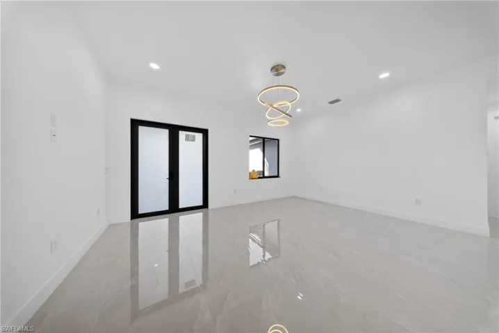 Empty room featuring french doors, hanging lights, and light marble finish floors
