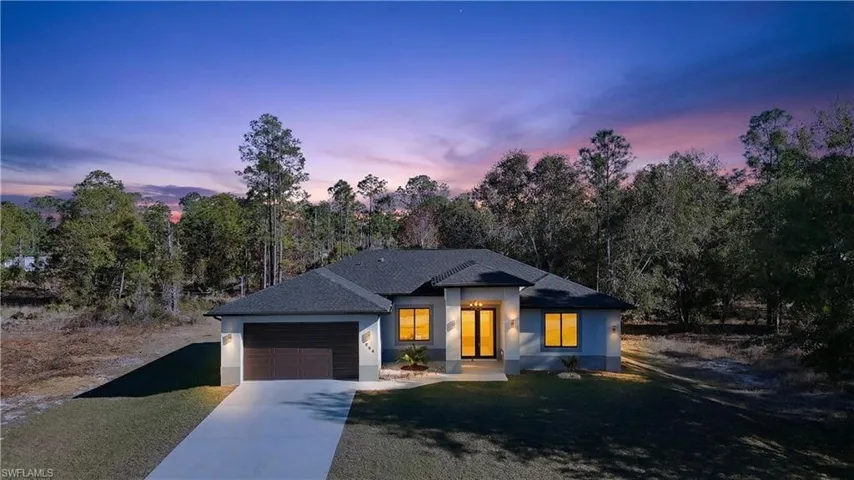 Modern farmhouse featuring a shingled roof, driveway, stucco siding, an attached garage, and a front yard