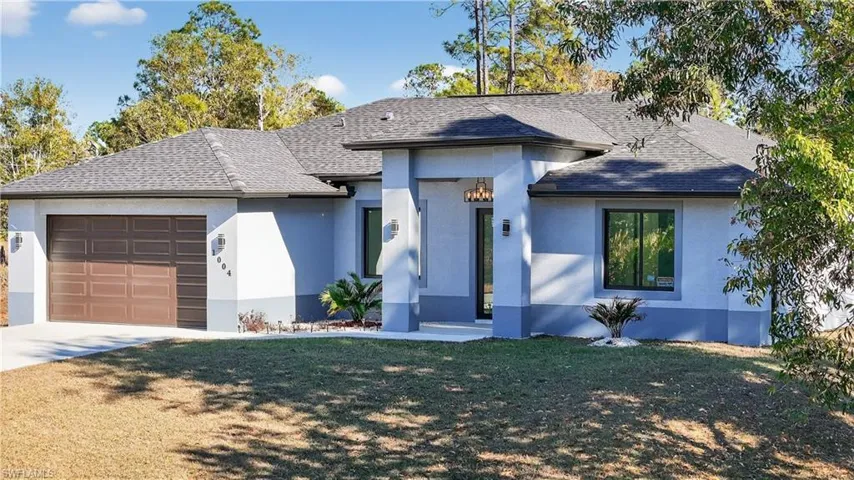 View of front of home with a garage, roof with shingles, a front lawn, and stucco siding