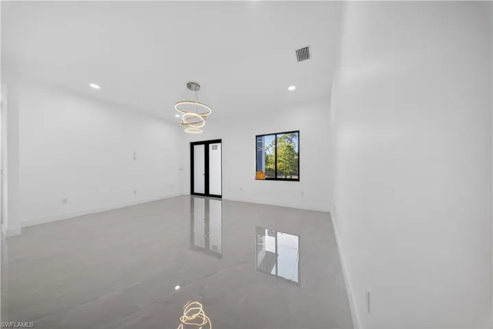 Unfurnished living room featuring suspended lighting and baseboards