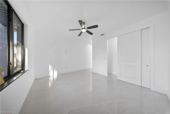 Unfurnished bedroom with a closet, a ceiling fan, and light marble finish flooring