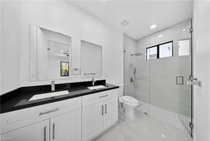Full bathroom with double vanity, a stall shower, plenty of natural light, and recessed lighting