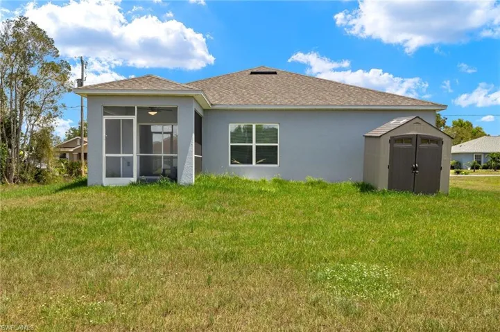 Back of property with a sunroom, a storage shed, and a yard