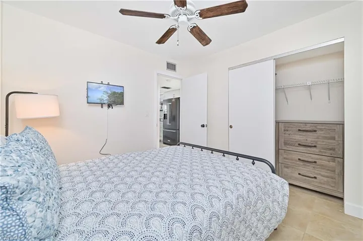 Bedroom featuring high end fridge, a closet, ceiling fan, and light tile patterned floors