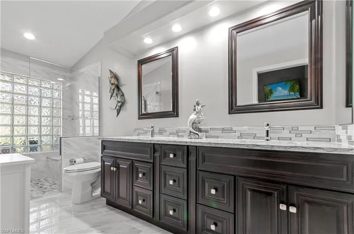 Full bathroom featuring marble finish floor, double vanity, toilet, a sink, and walk in shower