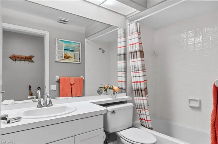 Full bathroom featuring visible vents, vanity, toilet, and shower / tub combo with curtain